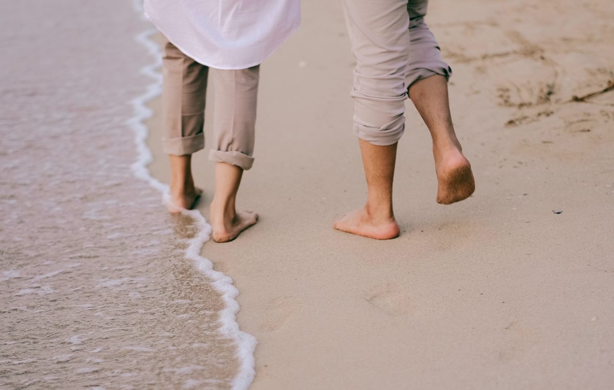 Pieds nus d'un couple marchant sur le sable en bord de mer