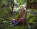 Charlotte Saint Jean fait une méditation pour se connecter à la Terre, seule, assise en tailleur sur une rocher, en pleine nature, dans la forêt.